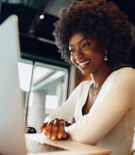 Smiling young african woman sitting with laptop in cafe, portrait